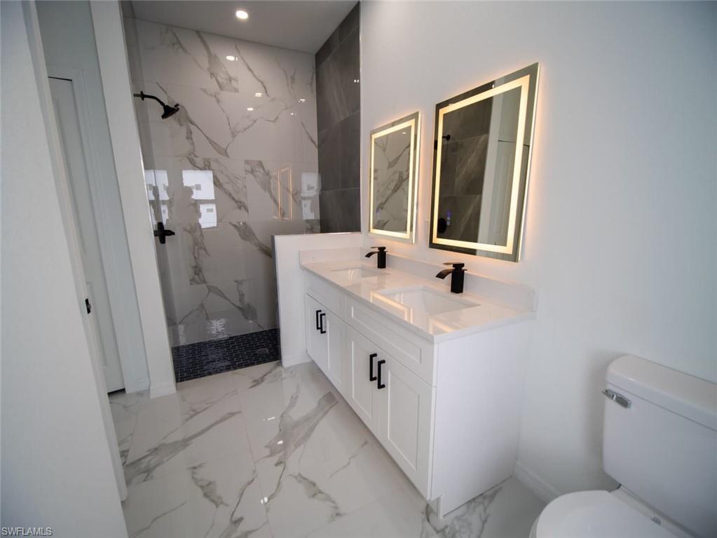 Master Bathroom with a marble finish shower, double vanity, and light marble finish flooring