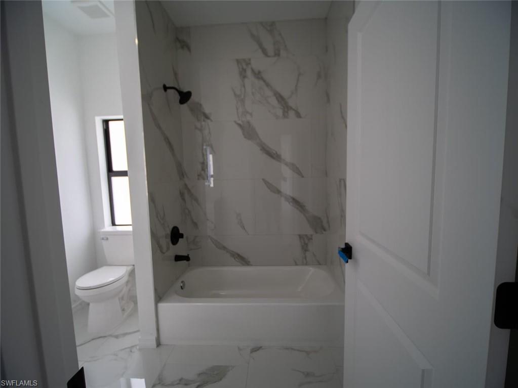 Full bathroom with a combined bath / shower with marble appearance and marble finish flooring
