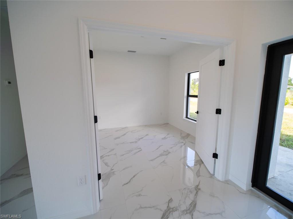 Spare room featuring light marble finish flooring and baseboards