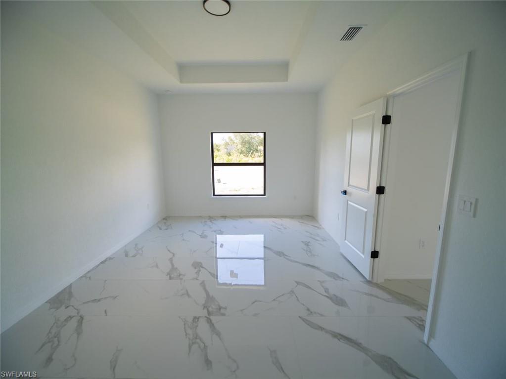 Bedroom with light marble finish flooring and a tray ceiling