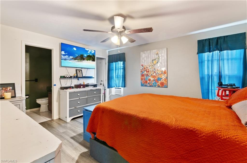Bedroom featuring light wood-style floors, a ceiling fan, and connected bathroom