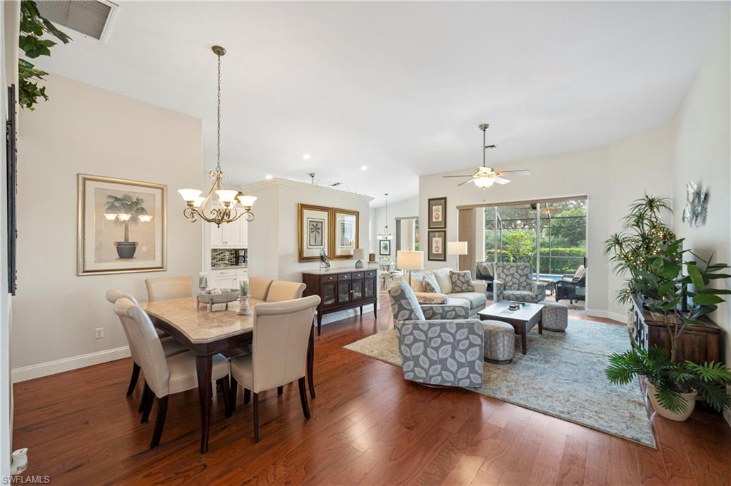 Dining area with dark wood-style floors, a ceiling fan, a chandelier, recessed lighting, and vaulted ceiling