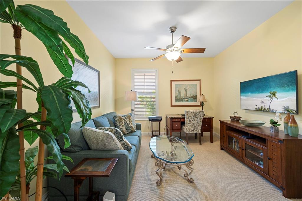 Living area featuring light carpet, an office area, and a ceiling fan
