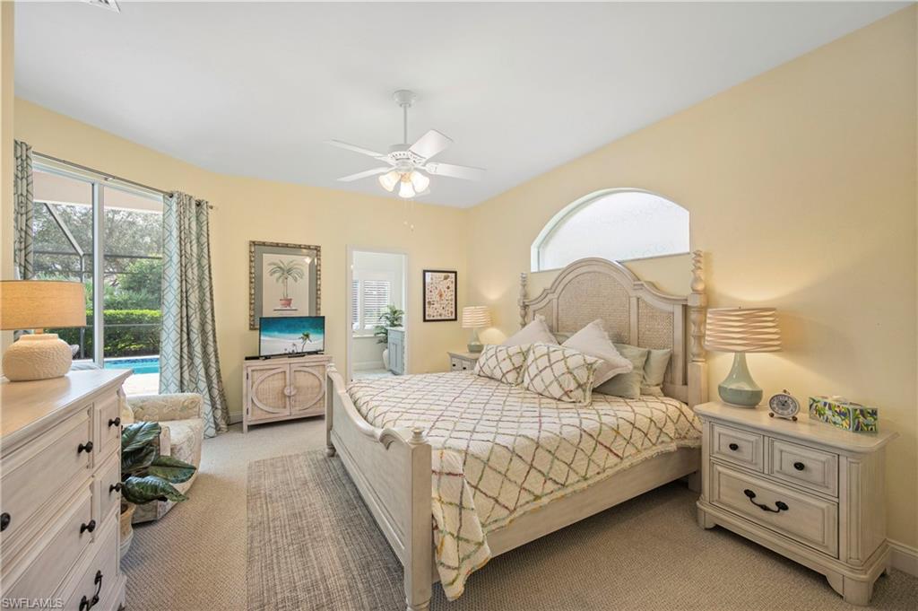 Bedroom with light carpet, multiple windows, a ceiling fan, and connected bathroom