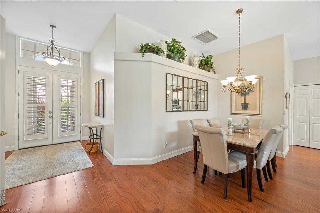 Dining space featuring a chandelier, wood finished floors, high vaulted ceiling, and french doors