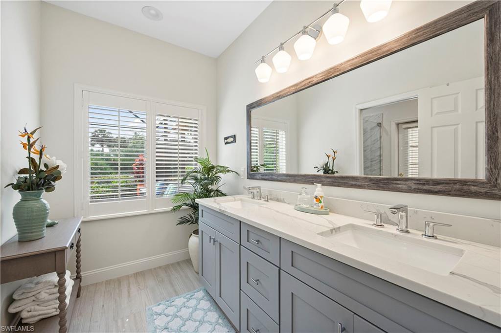 Bathroom featuring double vanity, light wood-style floors, and a shower