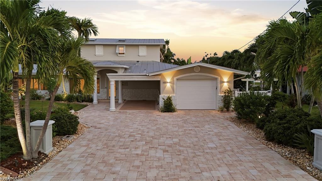 View of front facade with stucco siding, a garage, decorative driveway, and a metal roof