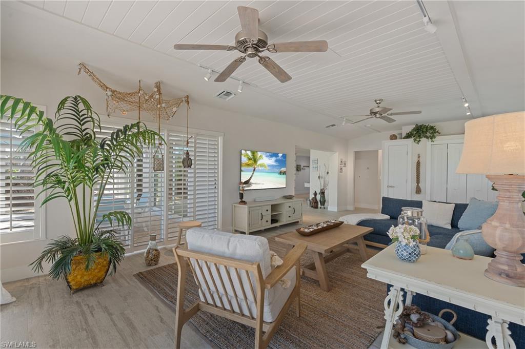 Living room with wood-look tile flooring, plenty of natural light, track lighting, and vaulted ceiling