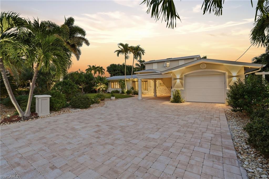 View of front of property with stucco siding, an attached garage, and driveway