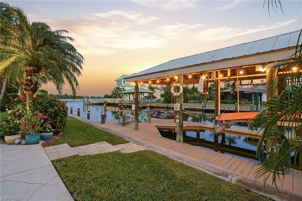 Dock featuring boat lift, a water view, and a yard -Virtually enhanced image