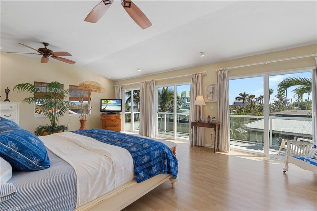 Bedroom featuring vaulted ceiling, ceiling fan, access to exterior, and light wood look tile floors