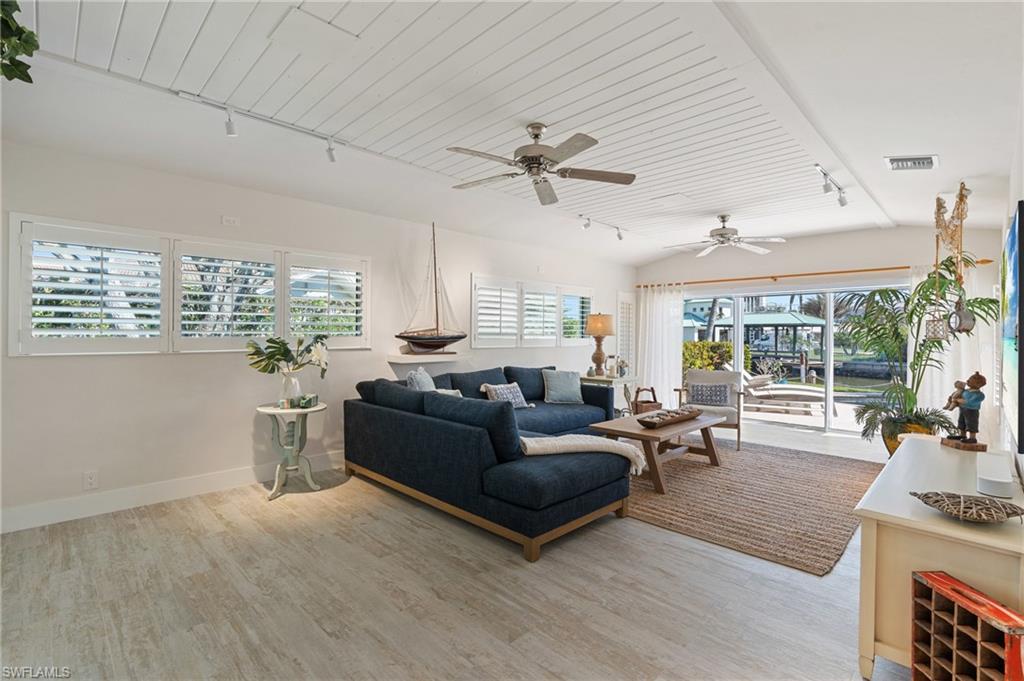 Living room featuring vaulted ceiling, track lighting, wood ceiling, and light wood look tile flooring