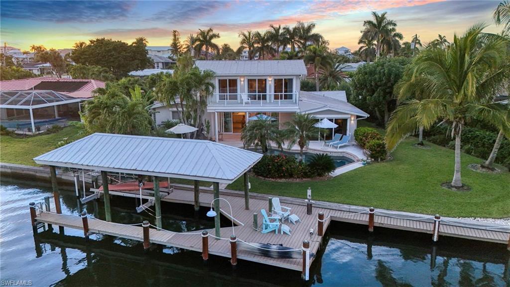 Dock area with a yard, boat lift, a water view, and a balcony - Virtually enhanced image