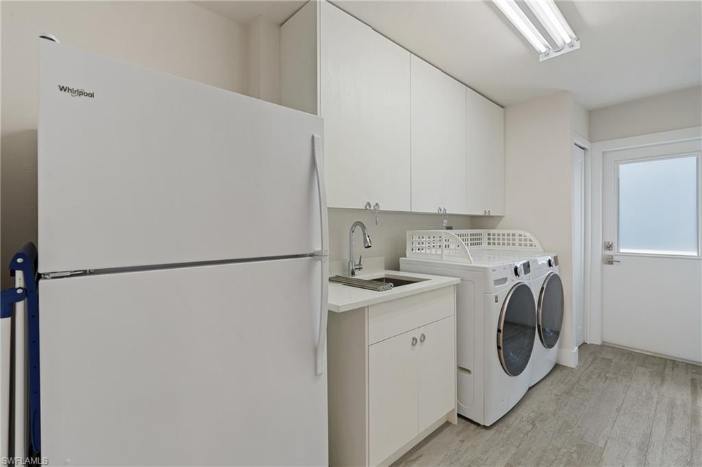 Clothes washing area featuring cabinets, separate washer and dryer, sink, and light wood look tile flooring