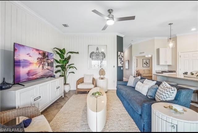 Living room featuring ornamental molding, light tile patterned floors, and ceiling fan