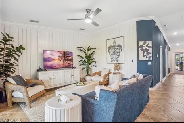 Living area with ornamental molding, tile patterned flooring, and a ceiling fan