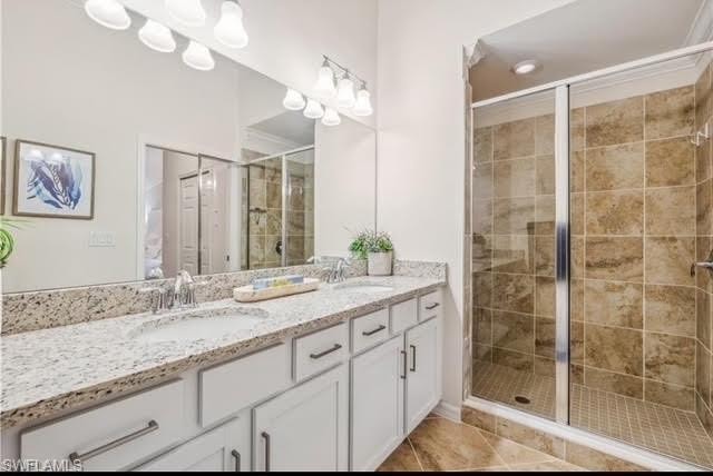 Bathroom with double vanity, a shower stall, and light tile patterned floors