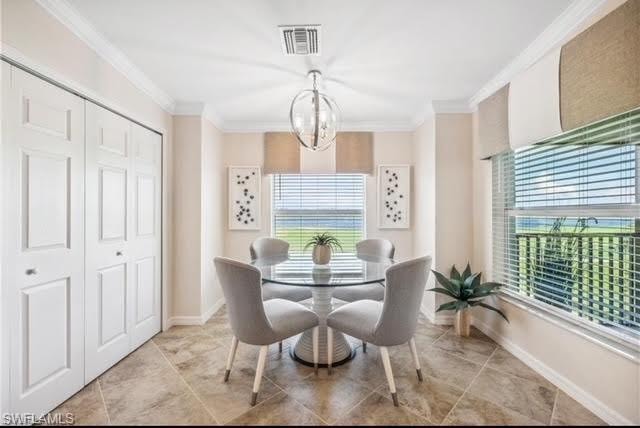 Dining room with healthy amount of natural light, ornamental molding, and a chandelier