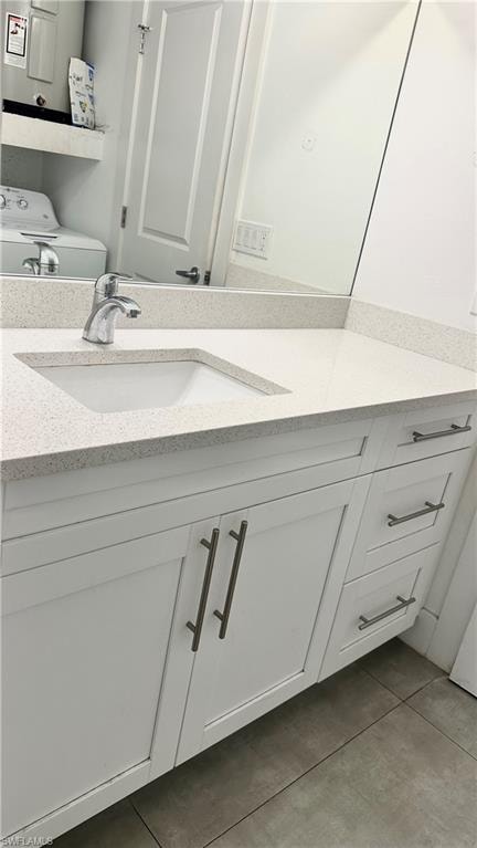 Bathroom featuring vanity, light tile patterned floors, electric water heater, and washer / dryer