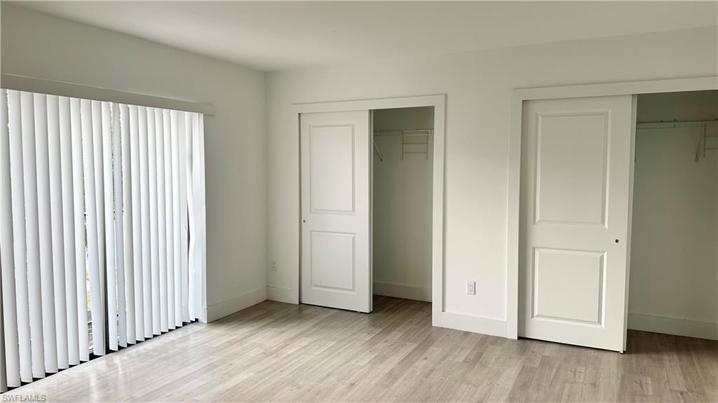 Unfurnished bedroom with two closets and light wood-style flooring