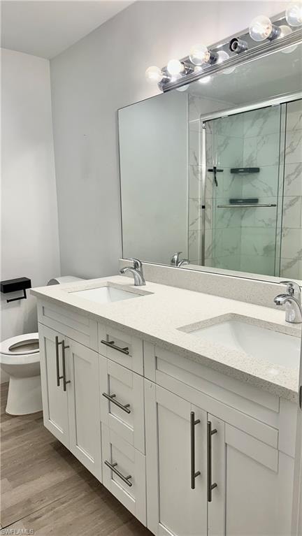 Full bathroom with double vanity, a marble finish shower, and light wood-style flooring