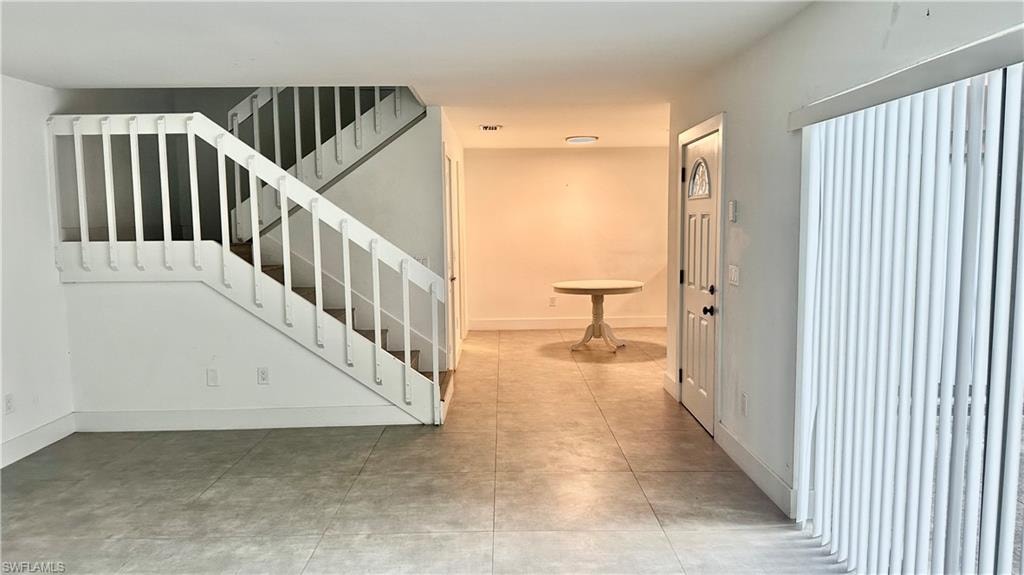 Stairway with baseboards and tile patterned flooring