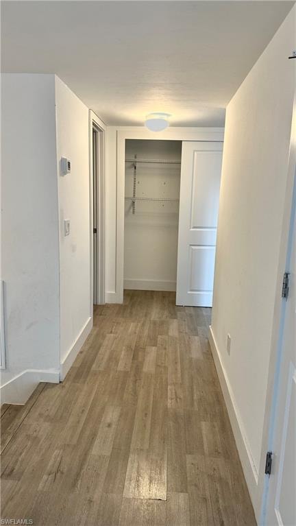 Corridor with light wood-type flooring and baseboards