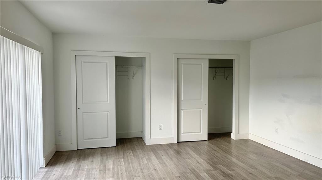 Unfurnished bedroom with two closets and wood finished floors