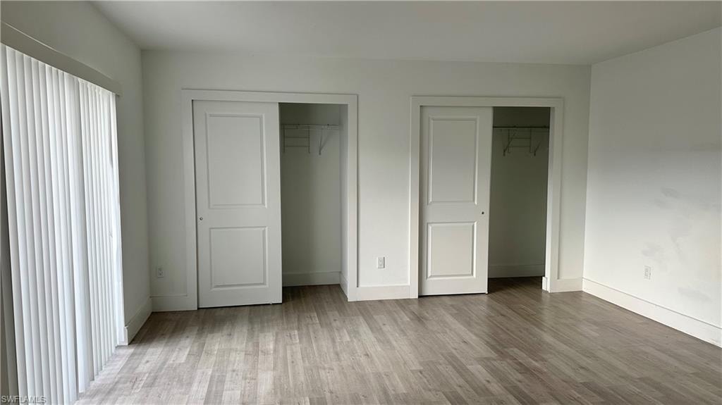 Unfurnished bedroom with multiple closets and wood finished floors