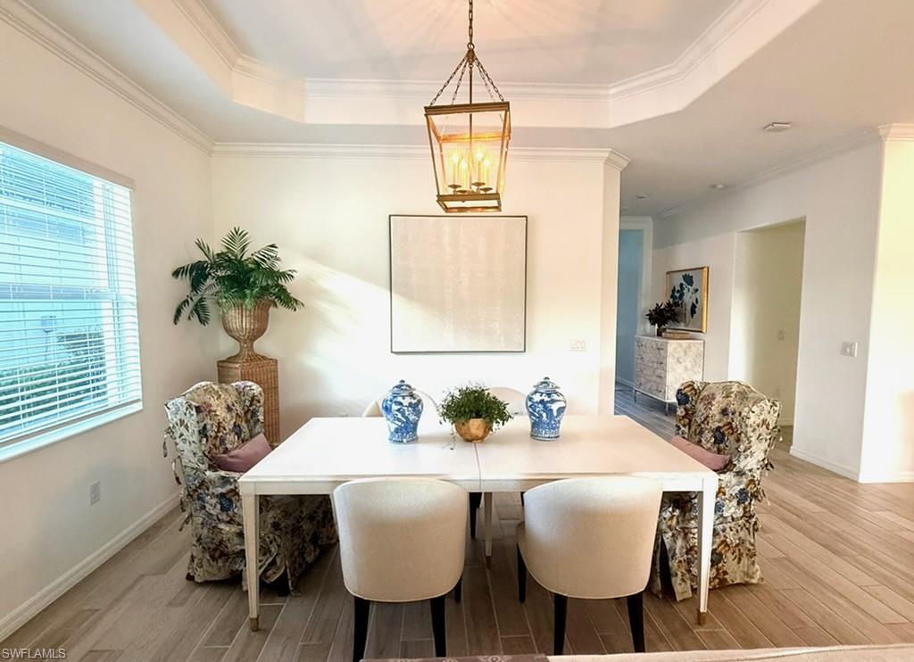 Kitchen featuring a breakfast bar, decorative light fixtures, a center island with sink, ornamental molding, and wood tiled floors