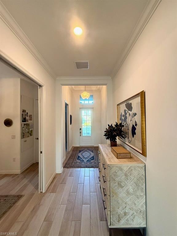 Corridor with ornamental molding and light wood-type flooring