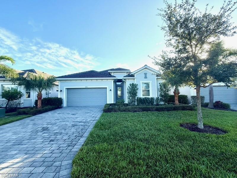 Ranch-style house with decorative driveway, an attached garage, a front yard, and a tile roof
