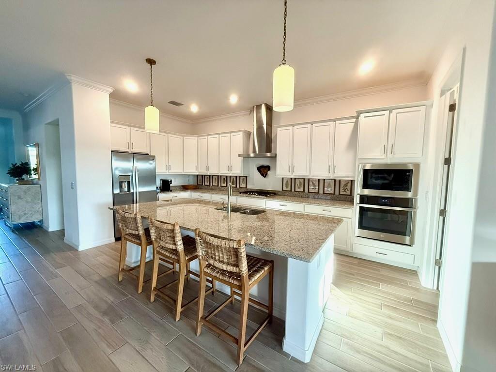 Dining area featuring light wood-type flooring, a tray ceiling, crown molding, and a chandelier