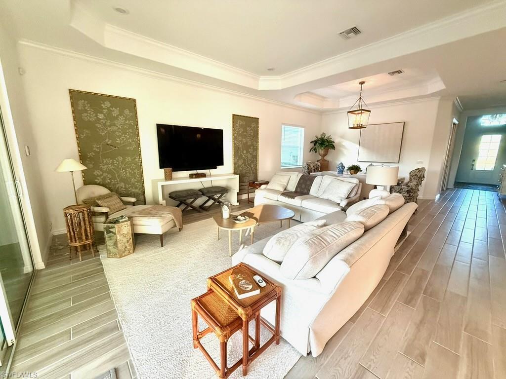 Kitchen with stainless steel appliances, wood tiled floors, ornamental molding, hanging light fixtures, and a kitchen breakfast bar