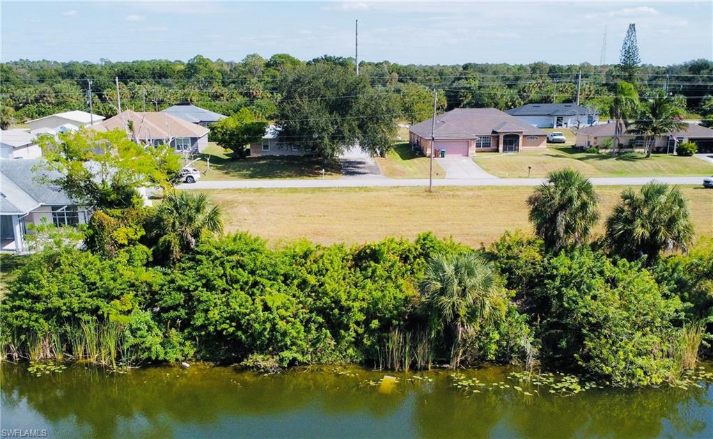 Aerial perspective of suburban area featuring a large body of water and a tree filled landscape