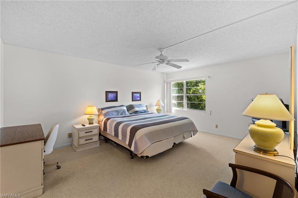 Bedroom featuring light colored carpet, a textured ceiling, and ceiling fan