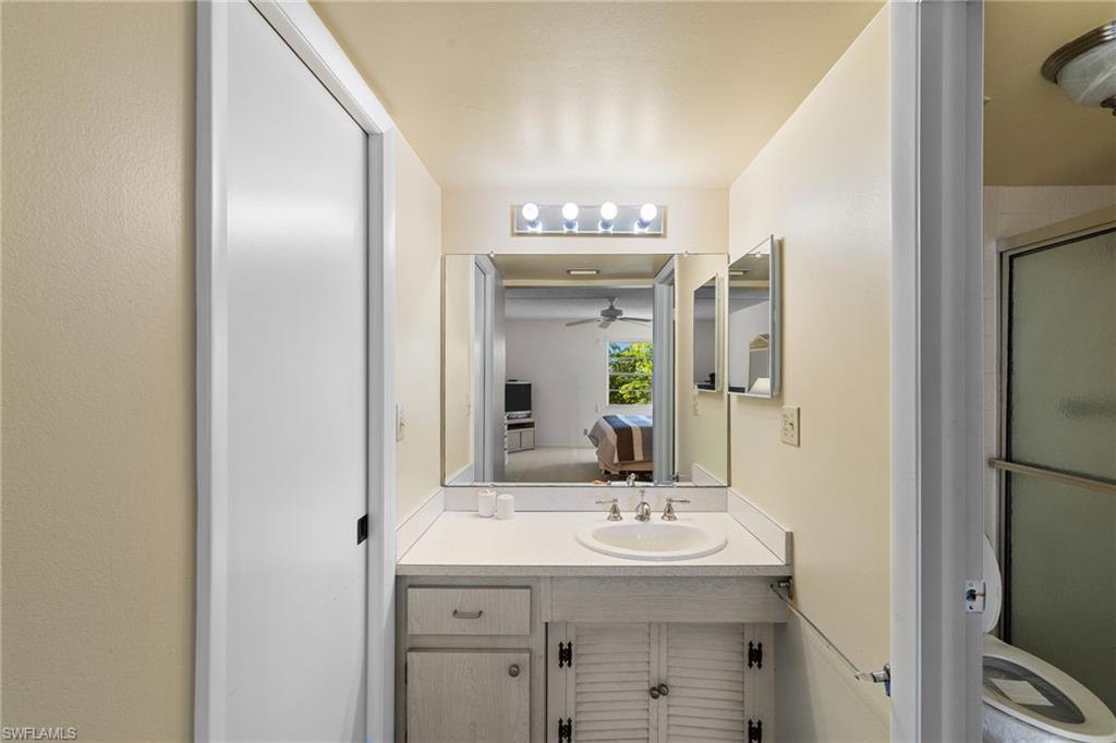 Full bathroom with ensuite bathroom, vanity, a ceiling fan, and a shower with door