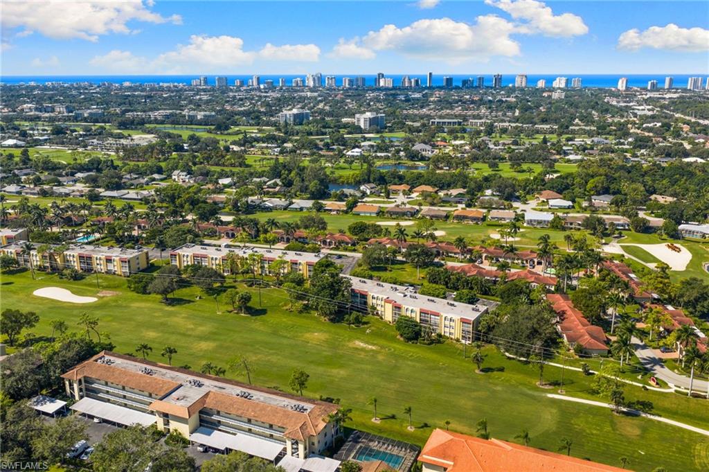 Drone / aerial view of skyline, a nearby body of water, and a golf club