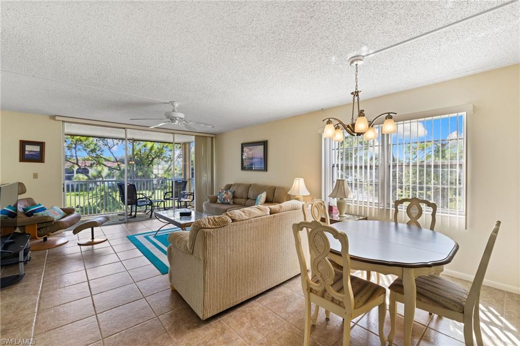 Dining space featuring tile patterned floors, a ceiling fan, a textured ceiling, a chandelier, and floor to ceiling windows