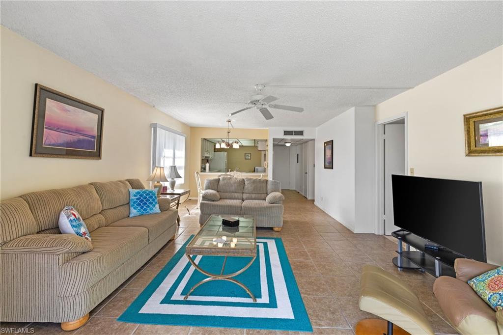 Living room with a textured ceiling, tile patterned flooring, and a ceiling fan