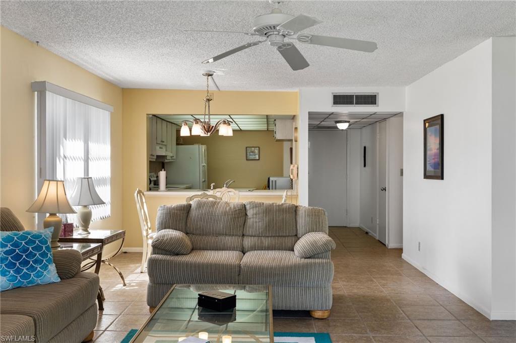 Living room with a textured ceiling, ceiling fan, and tile patterned floors