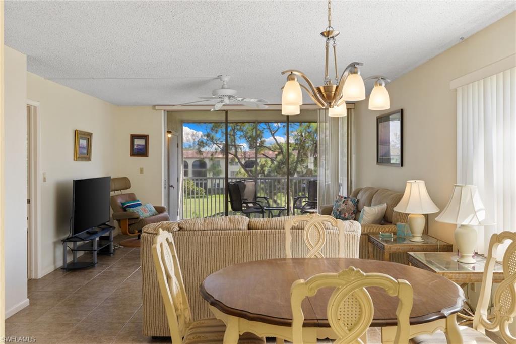 Dining room with a textured ceiling, tile patterned floors, a ceiling fan, and a chandelier