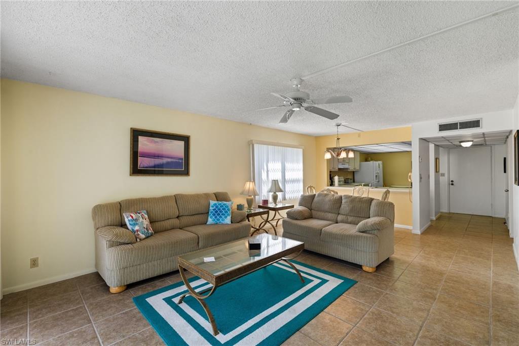 Living room featuring a textured ceiling, light tile patterned flooring, and a ceiling fan