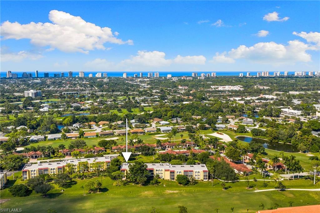 Drone / aerial view of city skyline, a nearby body of water, and a golf club