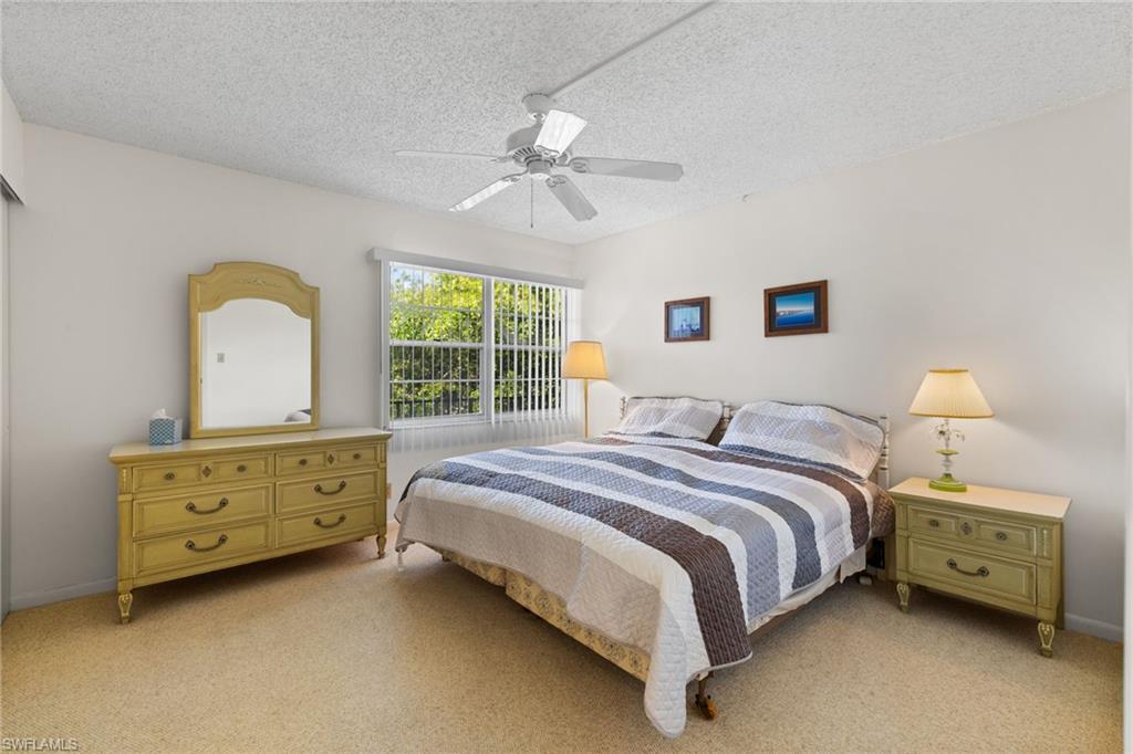 Bedroom with a textured ceiling, light carpet, and ceiling fan