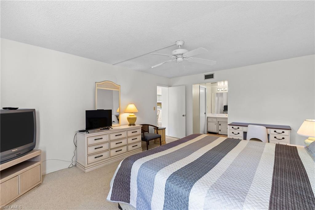 Bedroom with an office area, light carpet, a ceiling fan, and a textured ceiling