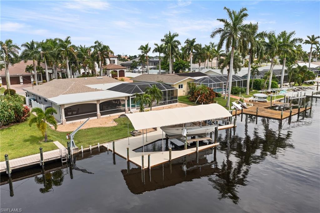 Dock area with boat lift, a water view, a residential view, and a lawn