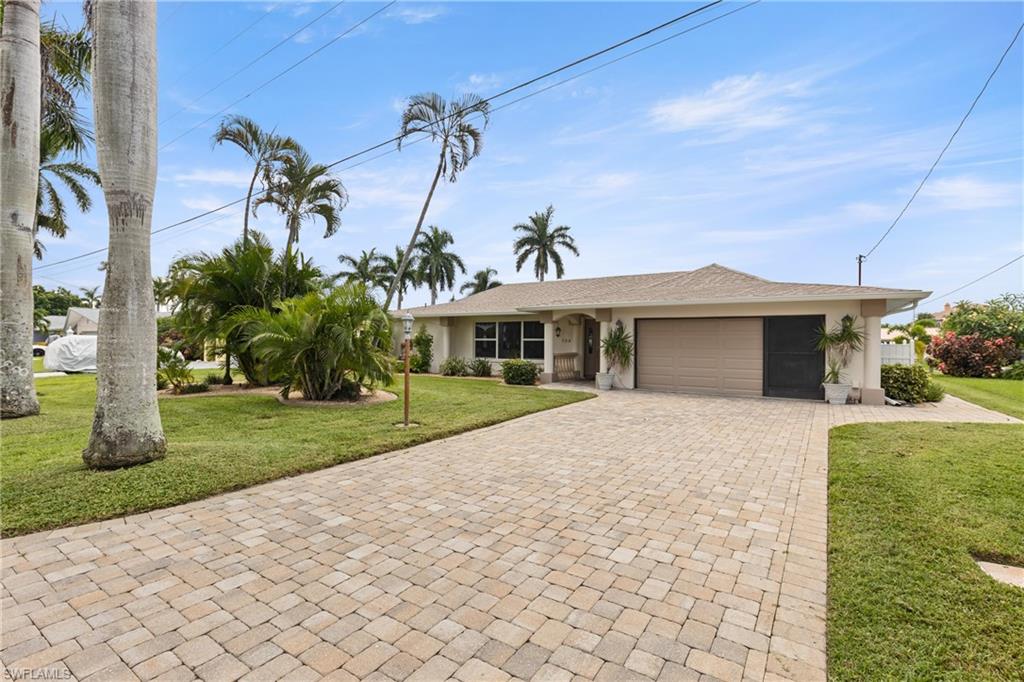 Single story home with an attached garage, a front yard, decorative driveway, and stucco siding