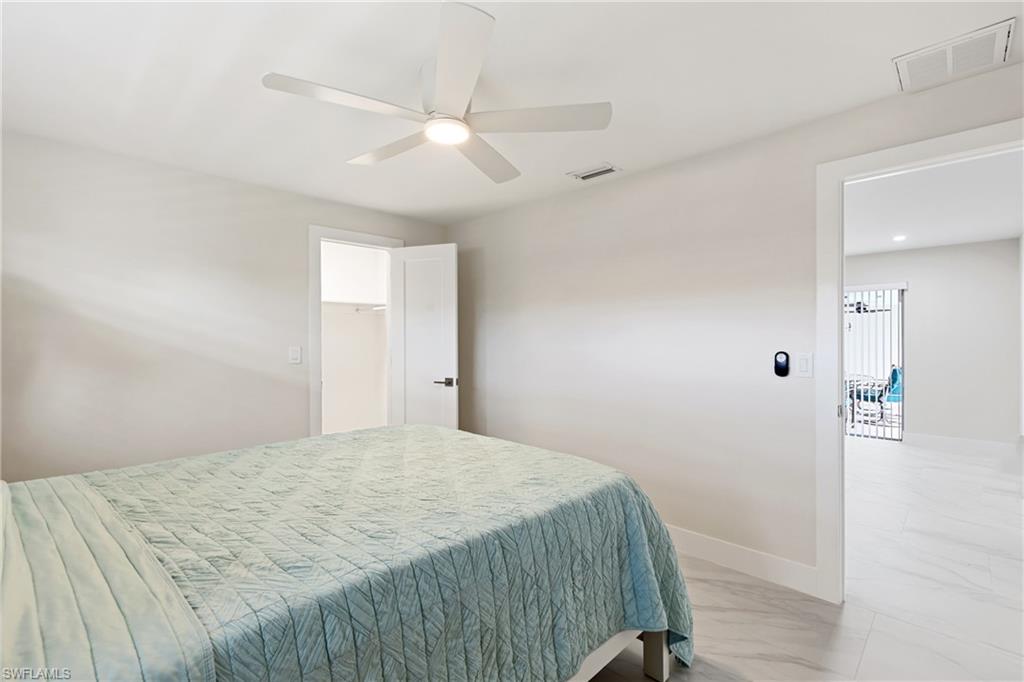 Bedroom featuring light marble finish floors, ceiling fan, and a walk in closet