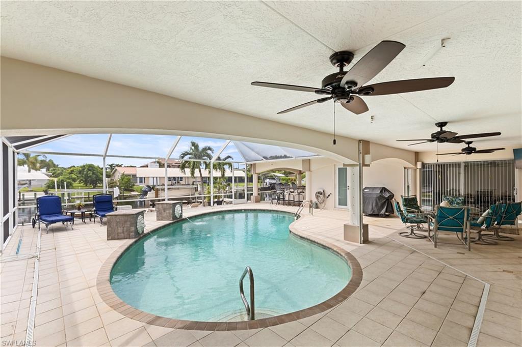 Outdoor pool featuring a patio area, a sunroom, grilling area, a ceiling fan, and glass enclosure